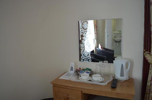 a mirror and a sink in a room at Globe Hotel in Colchester