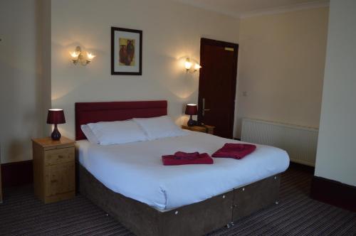 a bedroom with a bed with two red towels on it at Globe Hotel in Colchester