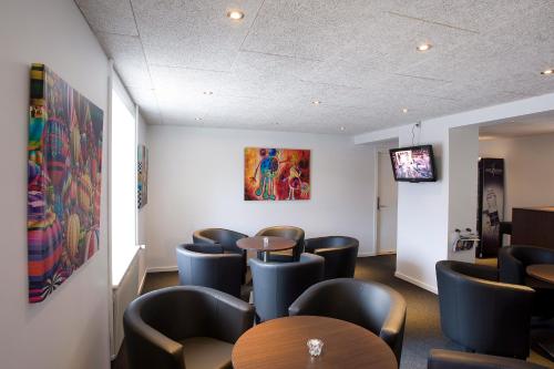 a waiting room with chairs and tables and a tv at Billum Kro in Billum