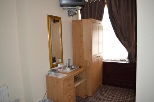 a room with a mirror and a wooden cabinet at Globe Hotel in Colchester