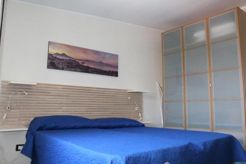Schlafzimmer mit einem Bett mit blauer Tagesdecke in der Unterkunft L'occhio sul Vesuvio appartamento con terrazza privata e casa vacanza senza terrazza privata in Neapel
