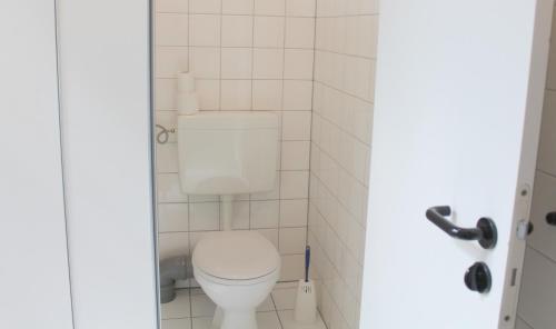 a bathroom with a toilet in a white tiled room at Die Fabrik - Hostel in Berlin