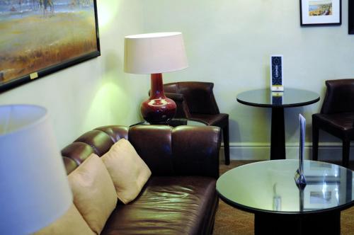 a living room with a leather couch and a lamp at St George's Hotel - Llandudno in Llandudno