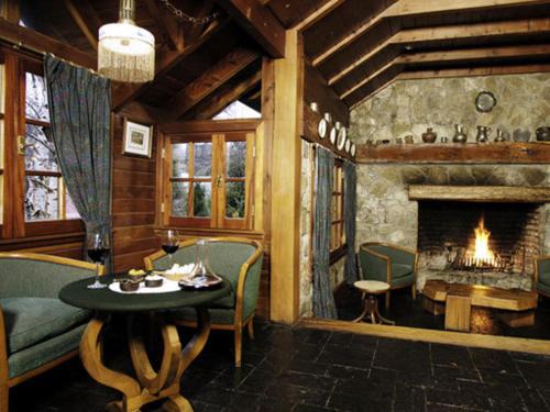 a living room with a table and a fireplace at Apart Hotel La Bora in San Martín de los Andes