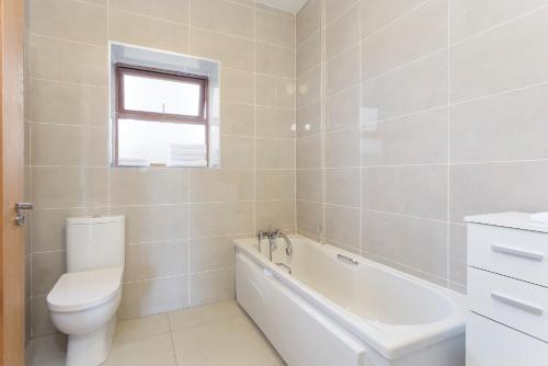 a bathroom with a toilet and a tub and a sink at Garryvoe Beach Homes in Garryvoe