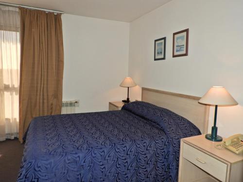 a hotel room with a blue bed and a window at Hotel Tres Cruces in Montevideo