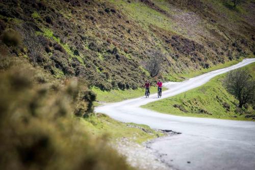two people riding bikes down a mountain road at Glan Llyn Farm House in Mold