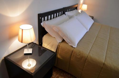 1 dormitorio con 1 cama y 1 mesa con lámpara en Bed & Breakfast Fontanarossa Airport -Private Parking-, en Catania