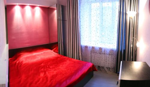 un letto rosso in una stanza con finestra di Apartment Dekabrystiv a Mykolaïv