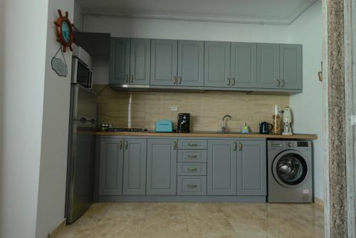 a kitchen with gray cabinets and a washing machine at Velier Apartment in Mamaia