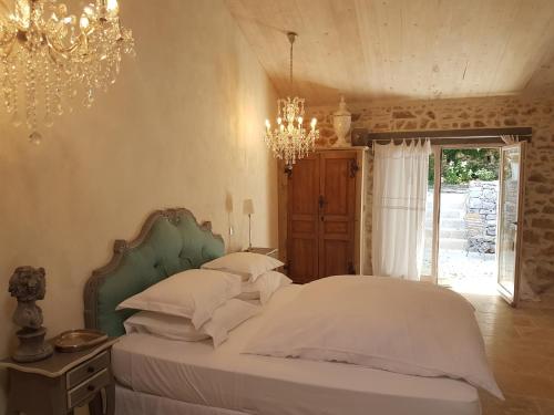a bedroom with a bed with white sheets and a chandelier at Le Domaine Saint Martin in Flassans-sur-Issole