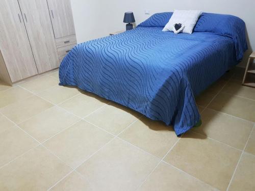 sypialnia z niebieskim łóżkiem i podłogą wyłożoną kafelkami w obiekcie Fiore di Loto w mieście Limatola
