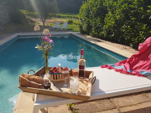 a table with a bottle of wine and bread next to a swimming pool at Le Domaine Saint Martin in Flassans-sur-Issole
