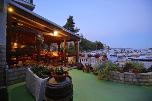 a building with a restaurant with a harbor in the background at Apartment and rooms Roko in Zaglav