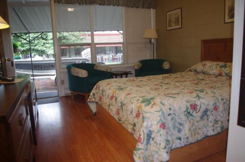 a bedroom with a bed and two chairs and a window at Capricorn Motel Royale 1000 Islands in Lansdowne