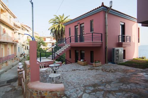 a pink house with a patio in front of the ocean at Mare Studios Exclusive in Plomarion