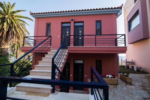 a pink house with stairs and a palm tree at Mare Studios Exclusive in Plomarion