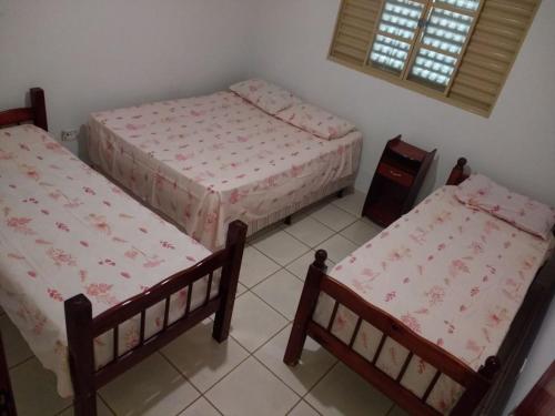 a room with three beds and a window at Casa beira thermas in Olímpia