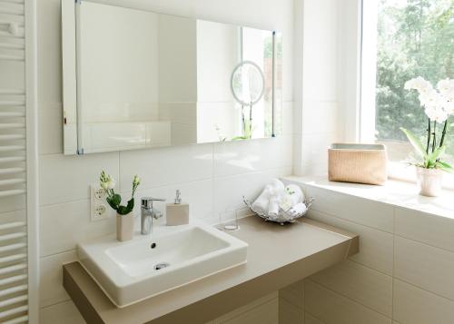 ein weißes Badezimmer mit Waschbecken und Spiegel in der Unterkunft Arion-Thale in Thale