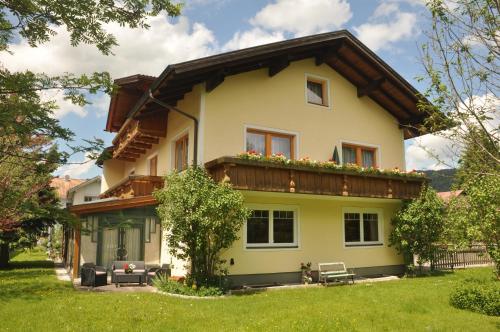 a yellow house with a wooden roof at Ferienwohnungen Eiblhuber in Tannheim