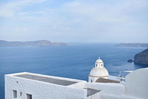a view of the ocean and a white building at Aroma Suites in Fira