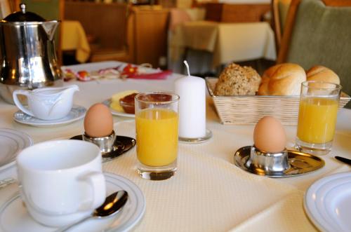 a table with eggs and juice and a basket of bread at Hotel Neuwirt in Brandenberg