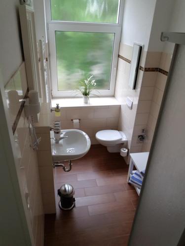 a bathroom with a window and a sink and a toilet at Pension Fischerjung in Rostock