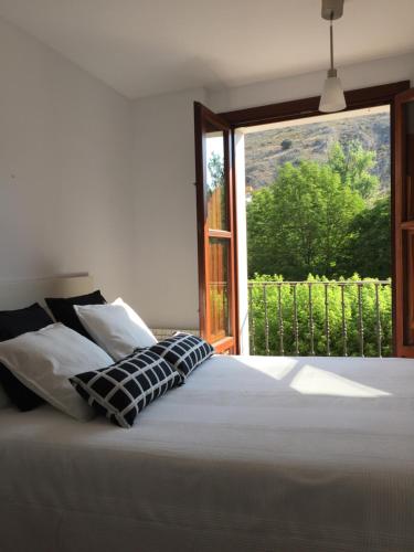 una camera da letto con un letto bianco con una grande finestra di Apartamentos Viejo Continente a Cuenca