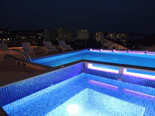a swimming pool at night with chairs and lights at Apartmani Niksic in Herceg-Novi