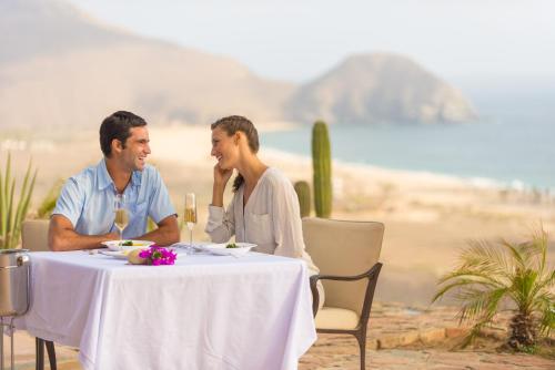 a man and woman sitting at a table on the beach at Guaycura Boutique Hotel, Beach Club & Spa in Todos Santos