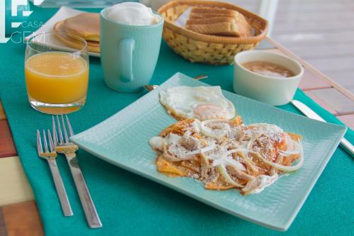 a plate of food on a table with a glass of orange juice at Casa Gem B&B in Playa del Carmen