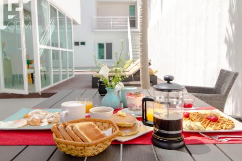 Casa Gem B&B في بلايا ديل كارمن: طاولة عليها طعام ومشروبات للإفطار