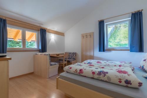 a bedroom with a bed and a table and windows at Appartements Haus Pichler in Eggen