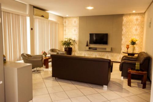 a waiting room with couches and a flat screen tv at Hotel Veneza in Brusque