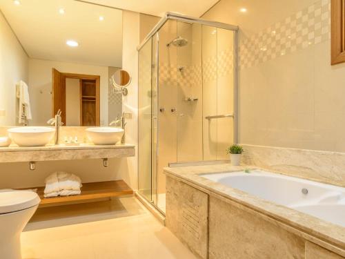 a bathroom with a tub and a shower and a toilet at Hotel Le Renard - Campos do Jordao in Campos do Jordão