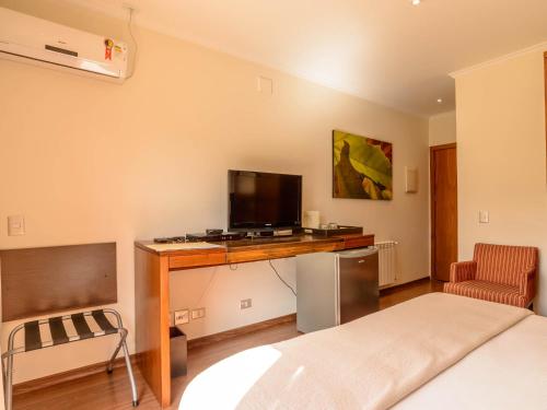 a bedroom with a desk with a television and a bed at Hotel Le Renard - Campos do Jordao in Campos do Jordão