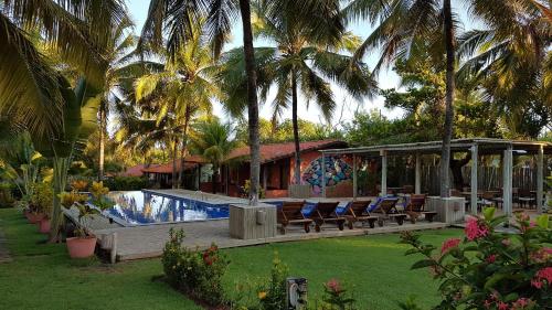 a resort with chairs and a swimming pool at Pousada Praia das Ondas - Pé na areia in Itacimirim
