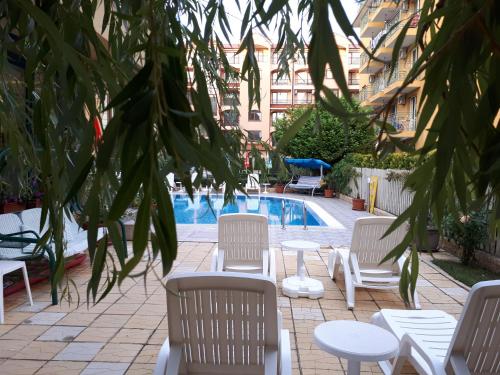 a group of white chairs and tables next to a pool at Aquaria Holiday Apartments in Sunny Beach