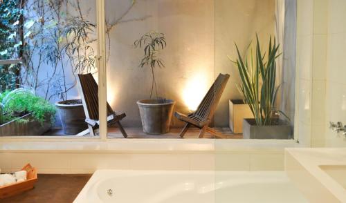 a bathroom with a window with two chairs and plants at Maitre Hotel Boutique in Buenos Aires