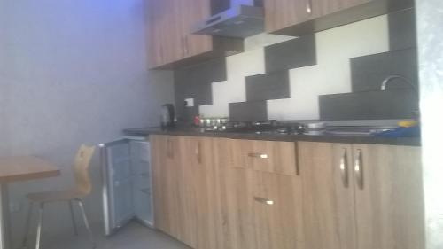 a kitchen with wooden cabinets and a sink and a chair at OldBatumi Apartment in Batumi
