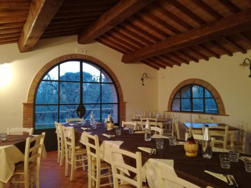 een eetkamer met tafels en stoelen en grote ramen bij Agriturismo Il Loghino in Palaia