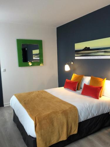 a bedroom with a large bed with red and yellow pillows at Hotel Ar Terra Nova in Saint Malo