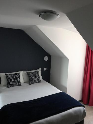 a bedroom with a black and white bed and red curtains at Hotel Ar Terra Nova in Saint Malo
