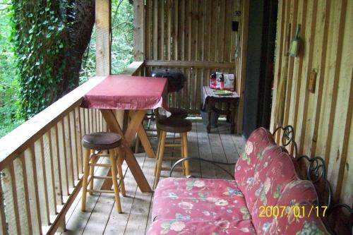 eine Veranda mit einem Tisch und Stühlen auf einer Terrasse in der Unterkunft Garden of Eden Cabins in Cosby