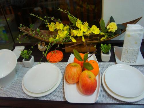 uma mesa com pratos brancos, maçãs e flores em Shejoje Poshtel Hostel em Cebu