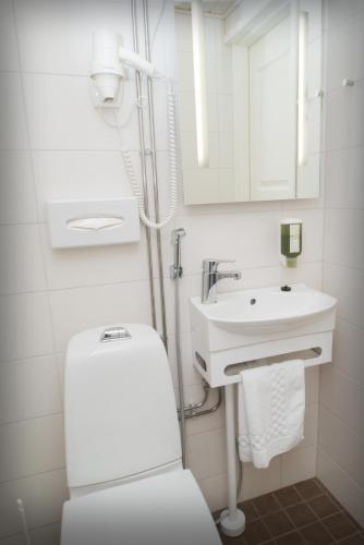 a white bathroom with a toilet and a sink at Hotel Golden Dome Iisalmi in Iisalmi