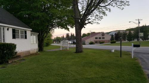 a street with a tree in the grass next to a house at Franconia Notch Motel in Lincoln