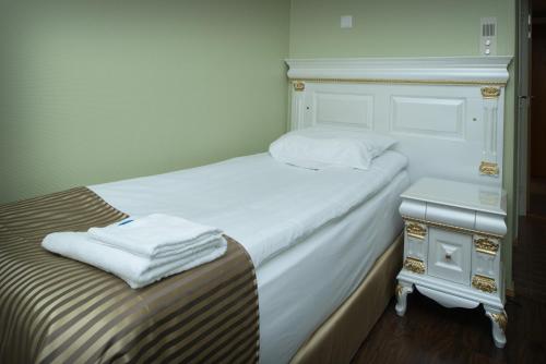 a bedroom with a bed and a nightstand with towels on it at Hotel Golden Dome Iisalmi in Iisalmi