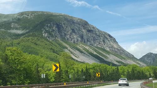 a car driving on a road near a mountain at Franconia Notch Motel in Lincoln