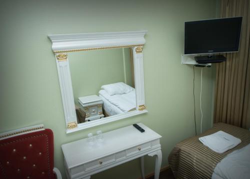 a hotel room with a mirror and a bed and a table at Hotel Golden Dome Iisalmi in Iisalmi